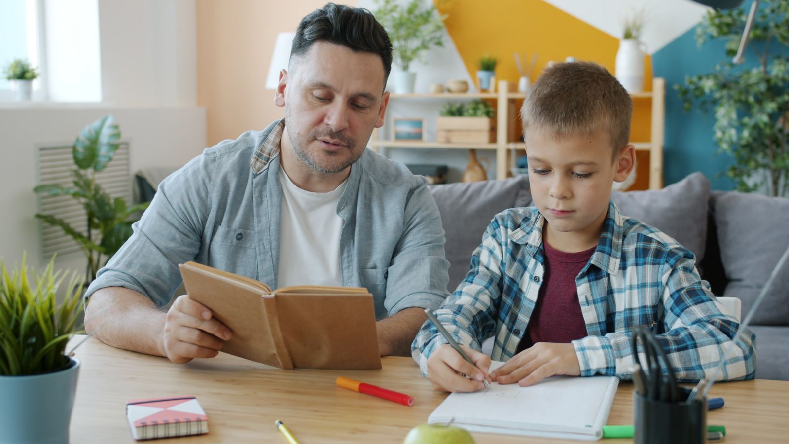 A father and son working on schoolwork together at a table
