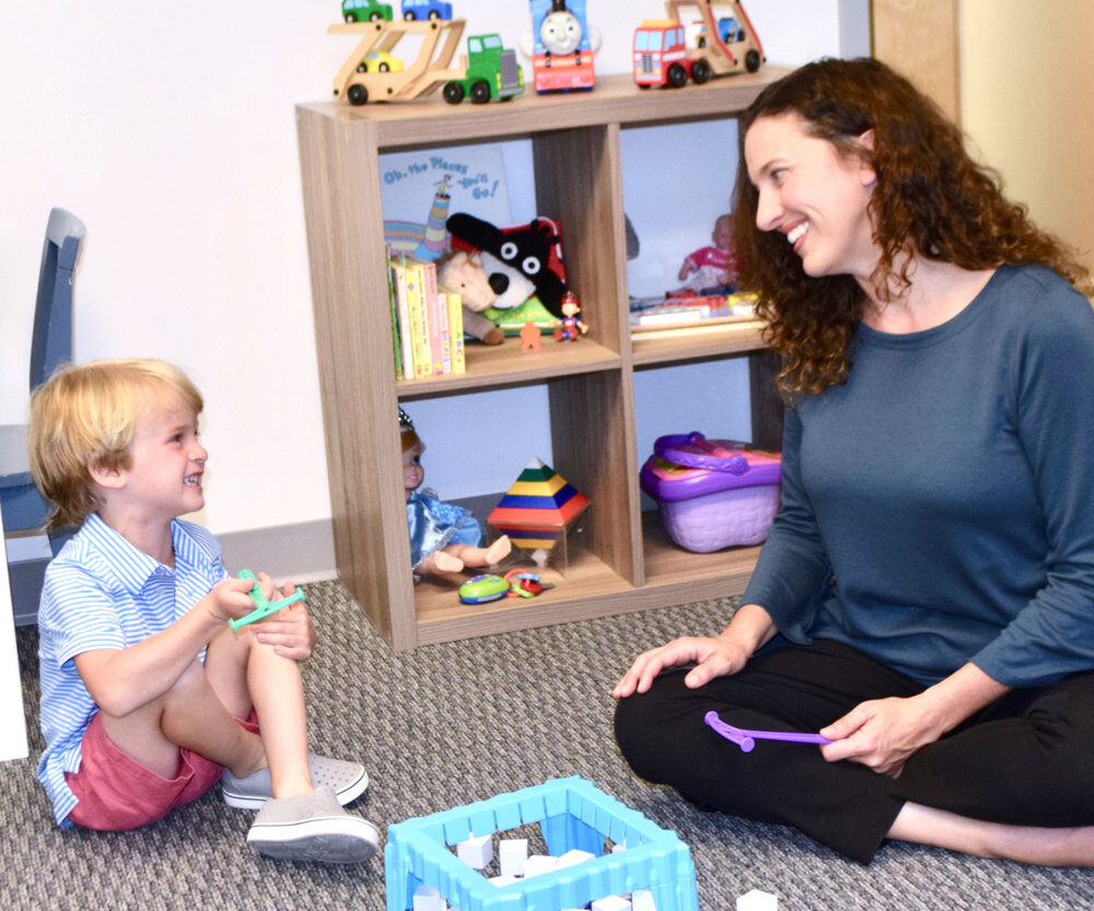 An Atlanta Children's Center clinician playing on the playroom floor with a young boy