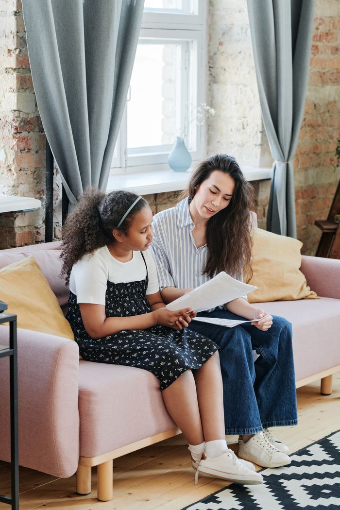 A mother and daughter reading together on a sofa