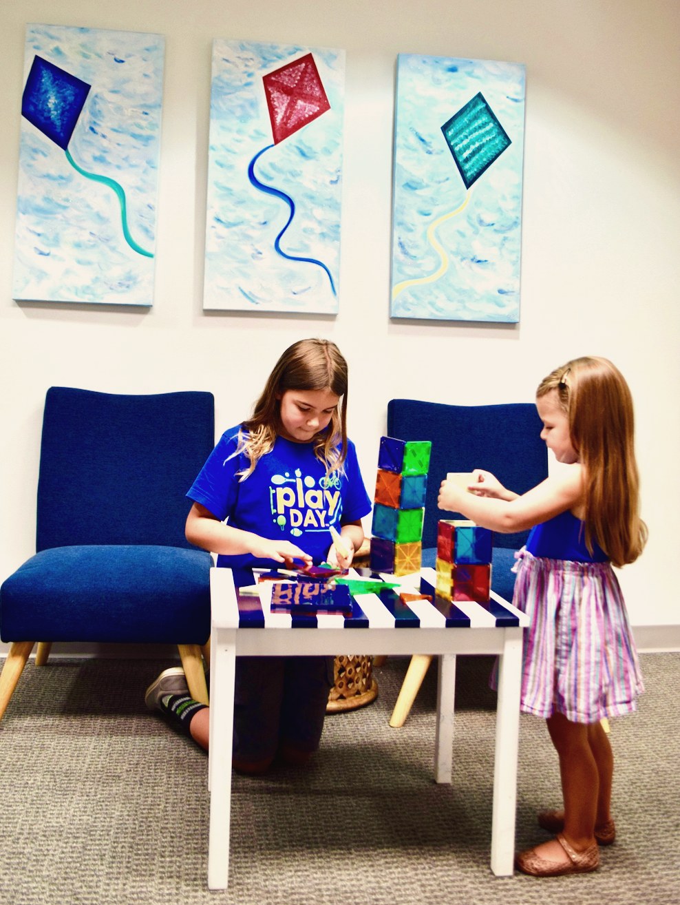 Two young girls building with colorful tiles in our playroom