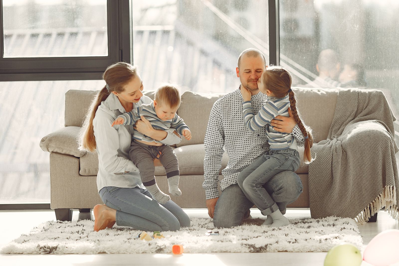A mother and father playing with their two young children in a bright living room