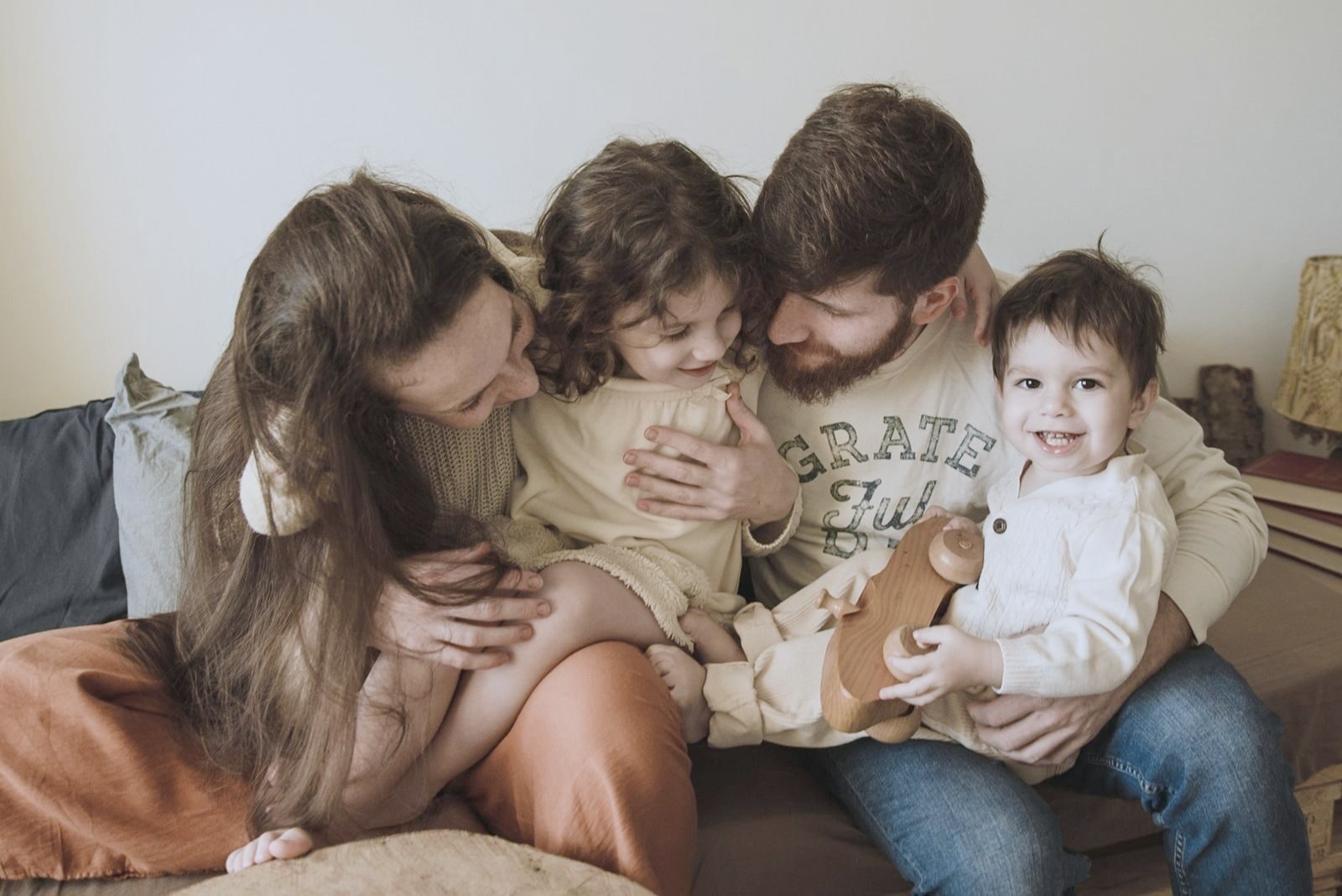 Parents relaxing on a sofa with their toddler and preschooler